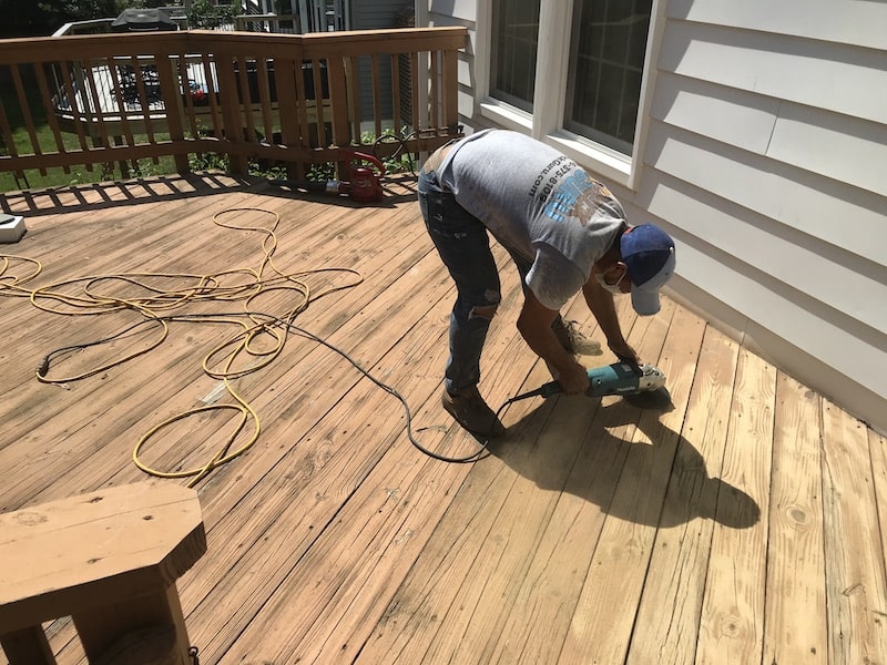 DeckGuru worker sanding old stain off a deck- types of deck stains